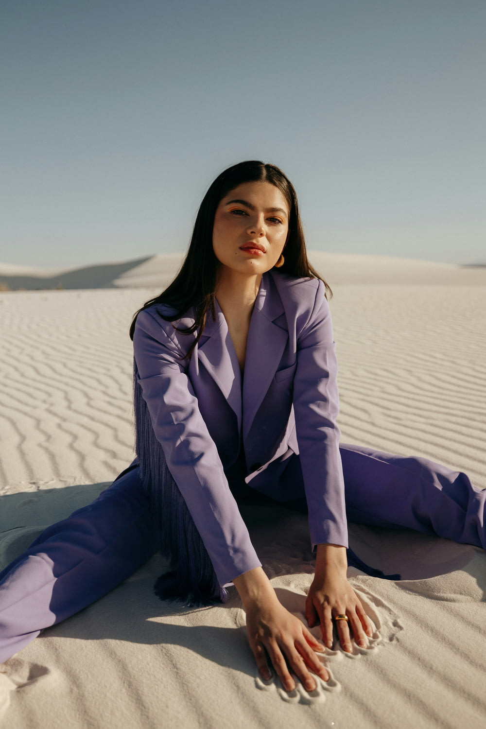 a woman in a purple suit sitting in the sand