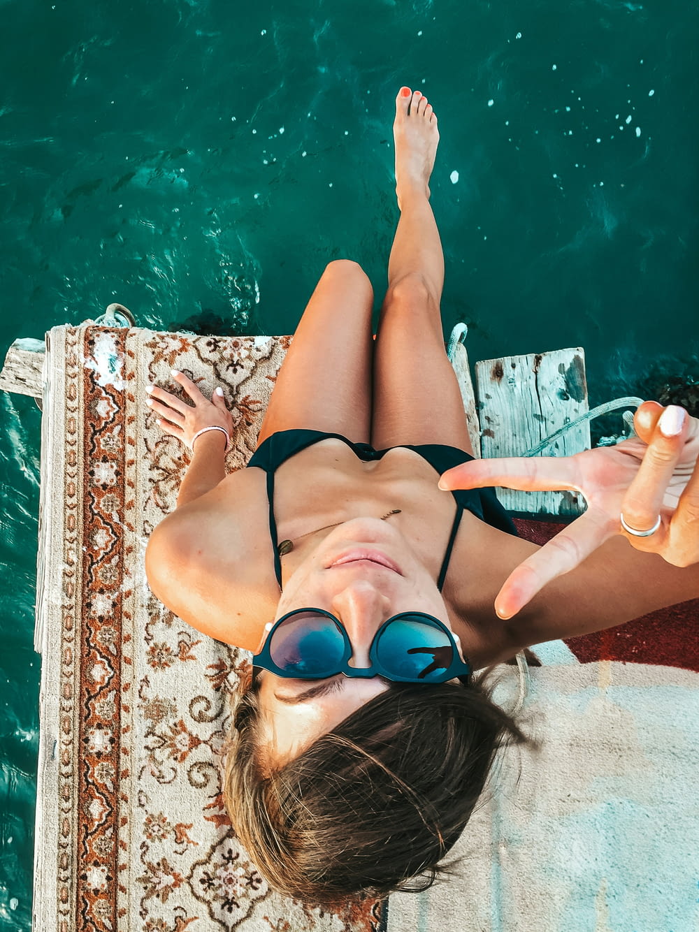 a woman in a bikini laying on a towel in the water