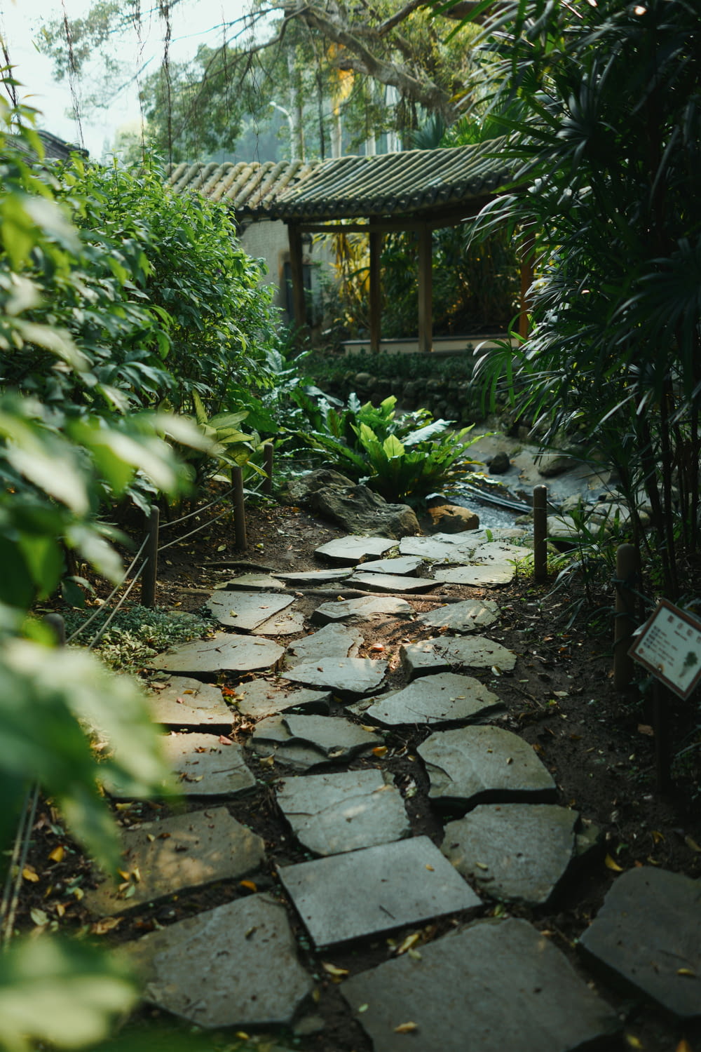 a stone path in a garden with a gazebo in the background