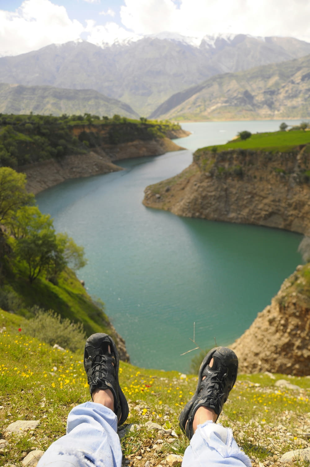 a person with their feet up on a hill overlooking a lake