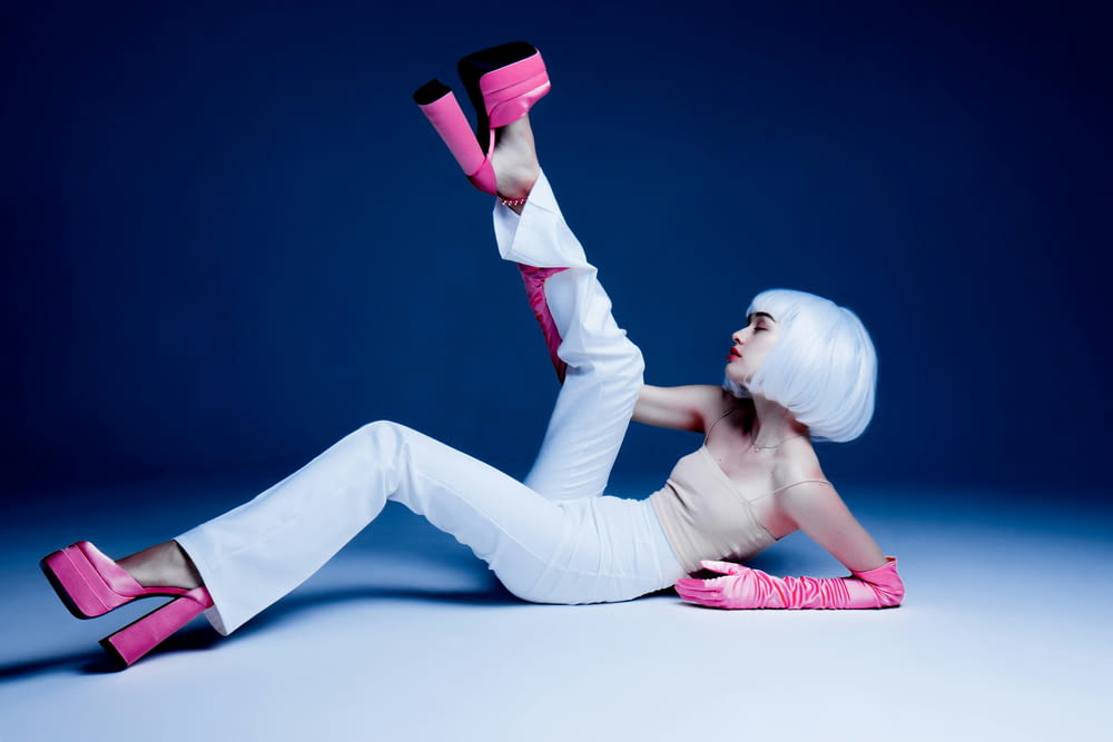 a woman with white hair and pink shoes laying on the ground