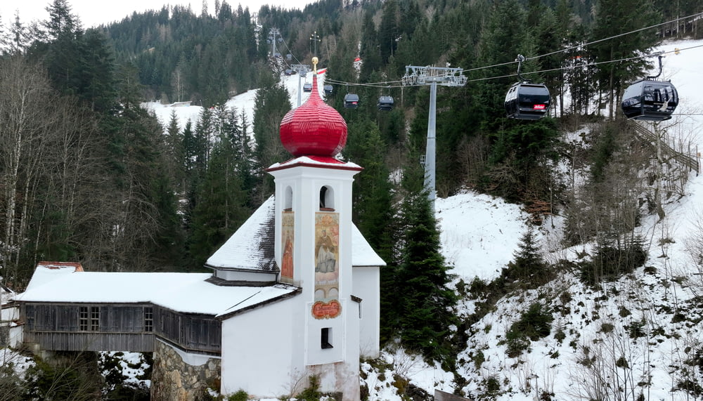 a white church with a red steeple and a ski lift in the background