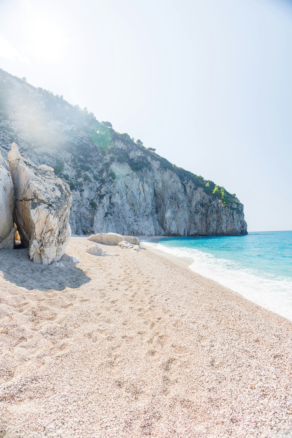 a sandy beach next to a rocky cliff