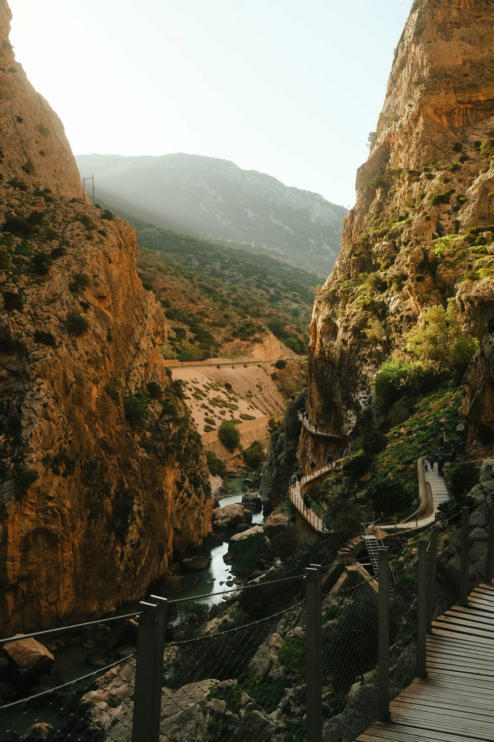 a wooden walkway next to a river in a canyon