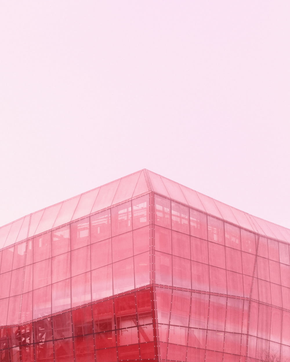 a red glass building with a clock on the top of it