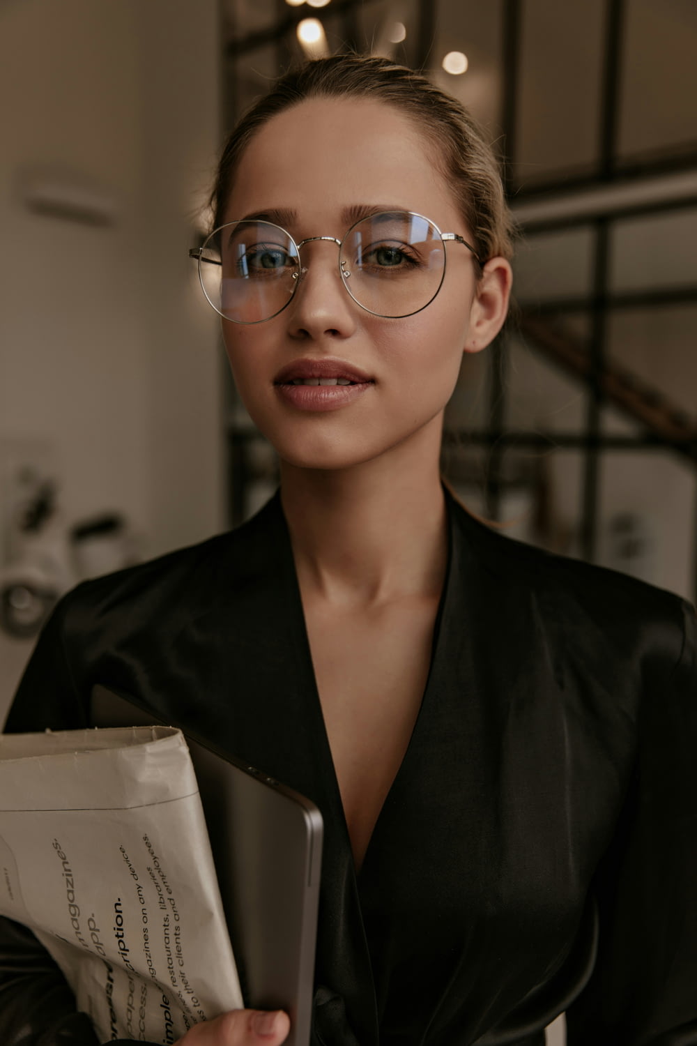 a woman wearing glasses holding a folder