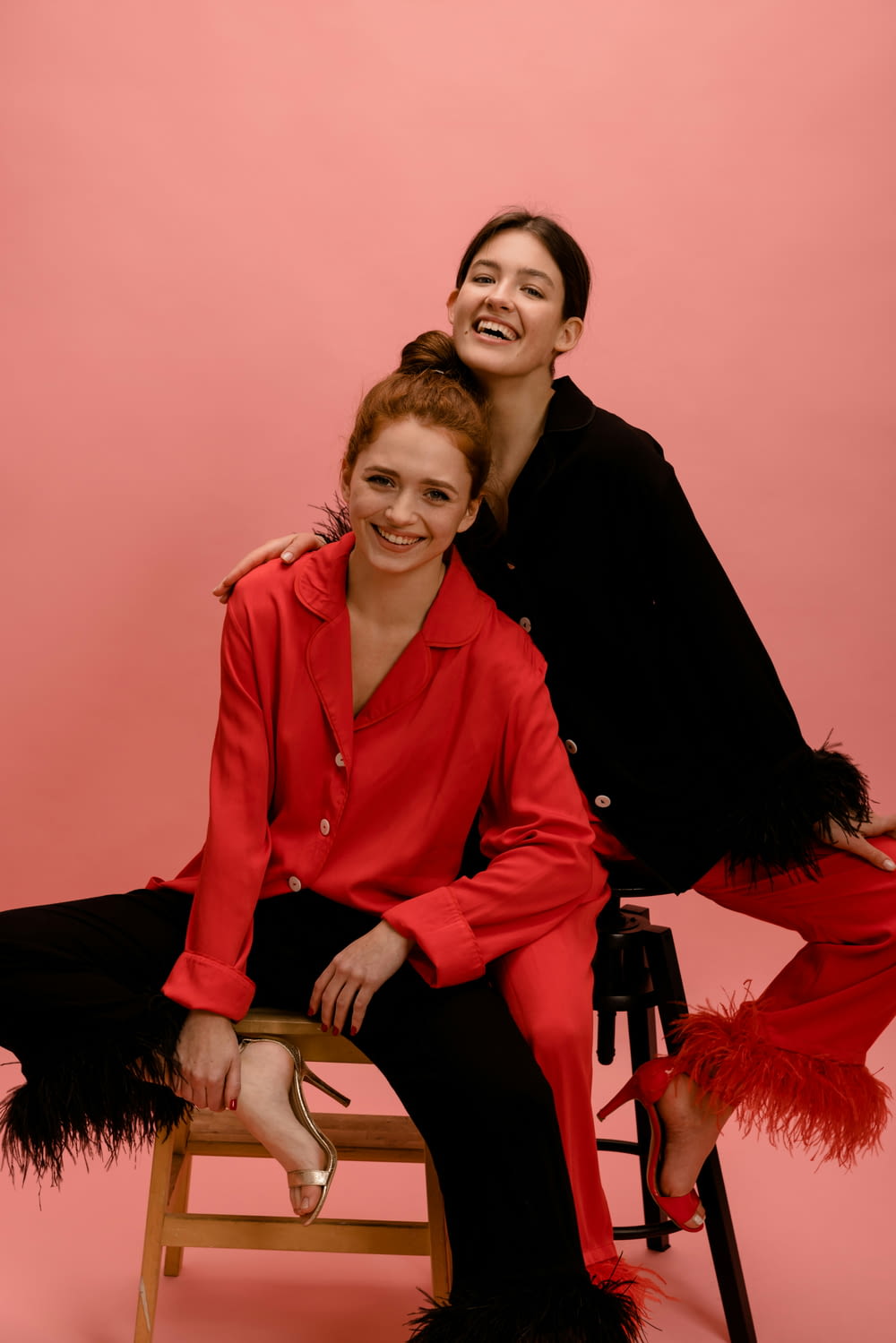 two women sitting on a stool posing for a picture