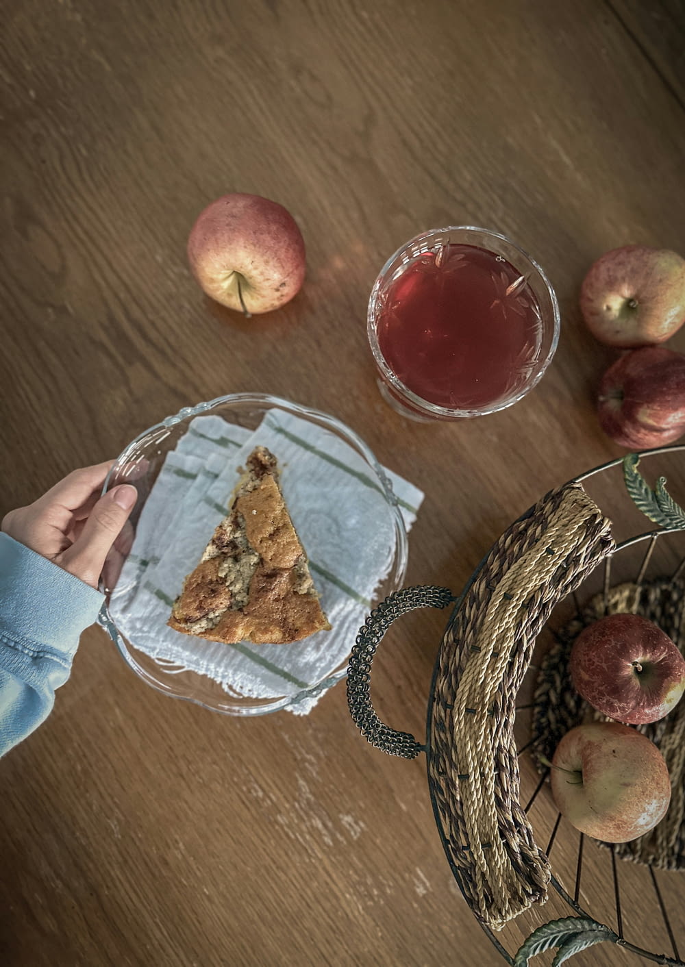 a person holding a piece of pie next to a basket of apples