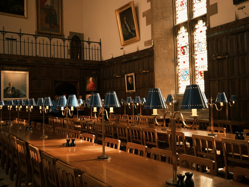 a long table with many chairs and lamps on it