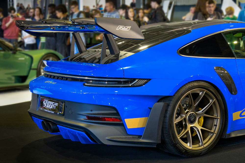 a blue sports car parked in front of a crowd of people