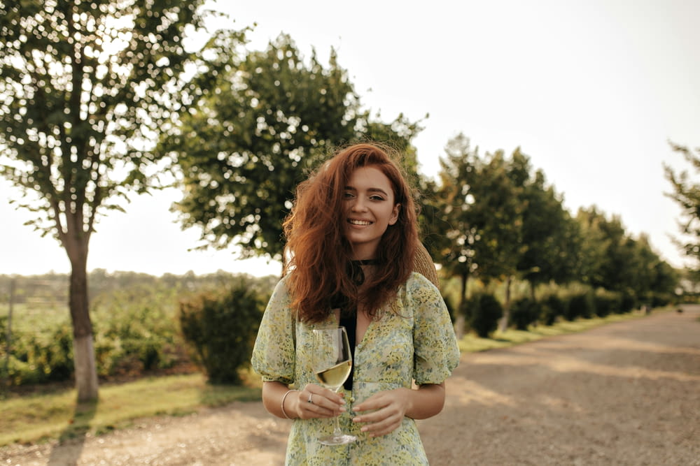a woman standing on a road holding a glass of wine