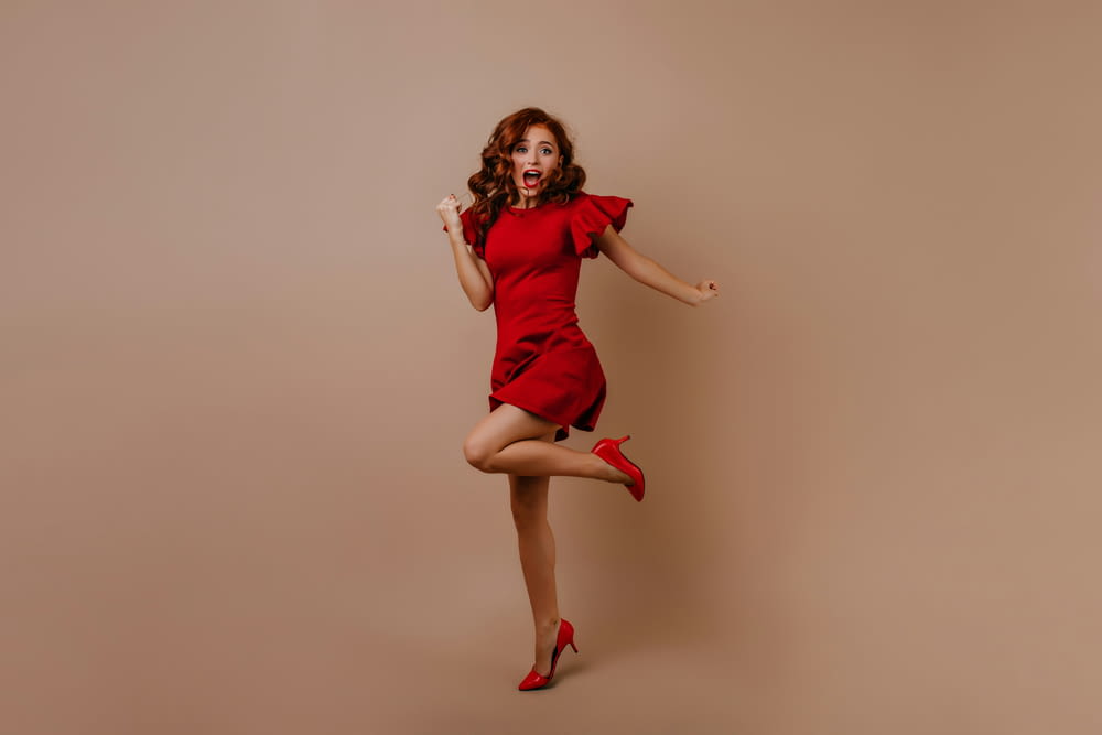 a woman in a red dress jumping in the air