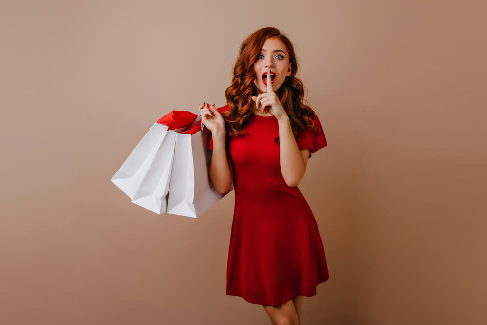 a woman in a red dress holding shopping bags