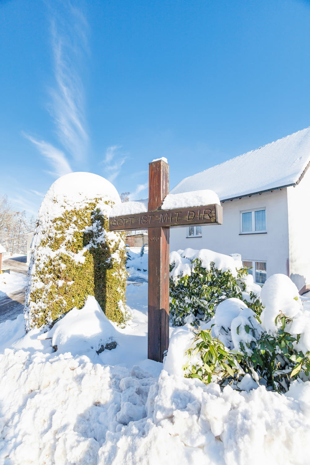 a wooden cross sitting in the middle of a snow covered yard