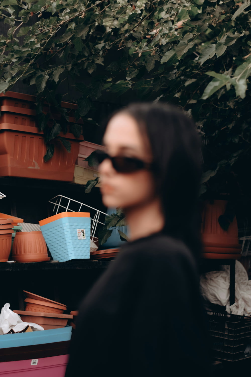 a woman standing in front of a shelf filled with potted plants
