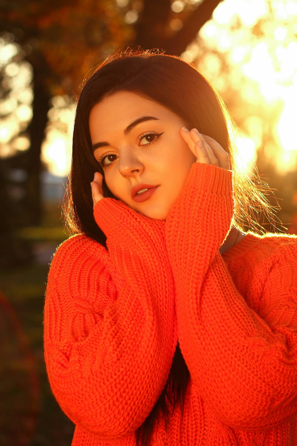 a woman in an orange sweater posing for a picture