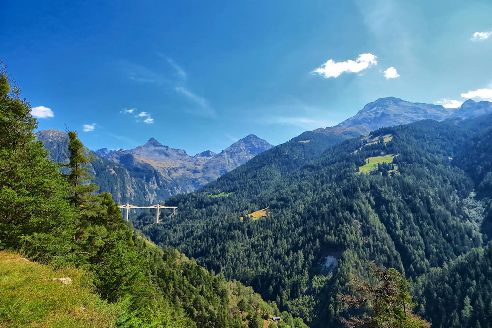 a scenic view of a mountain range with a bridge in the distance
