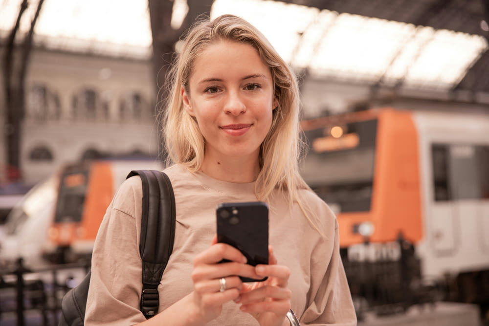 a woman holding a smart phone in a train station