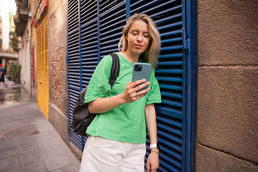 a woman in a green shirt is looking at her cell phone