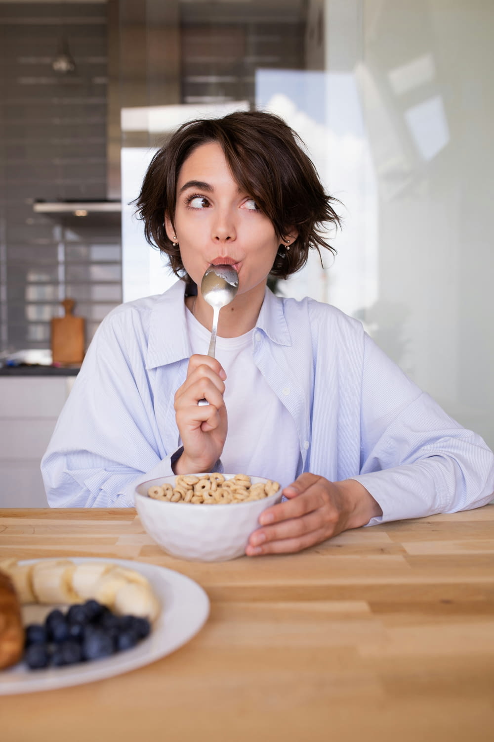 a woman holding a spoon over a bowl of cereal