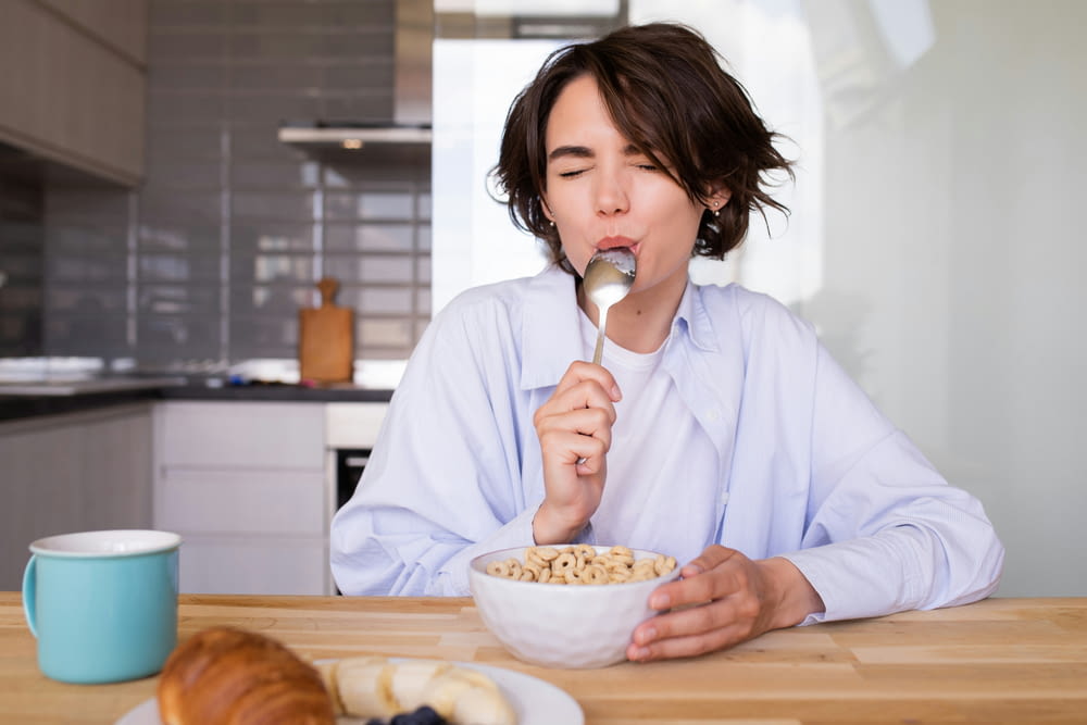 a woman eating cereal from a bowl with a spoon