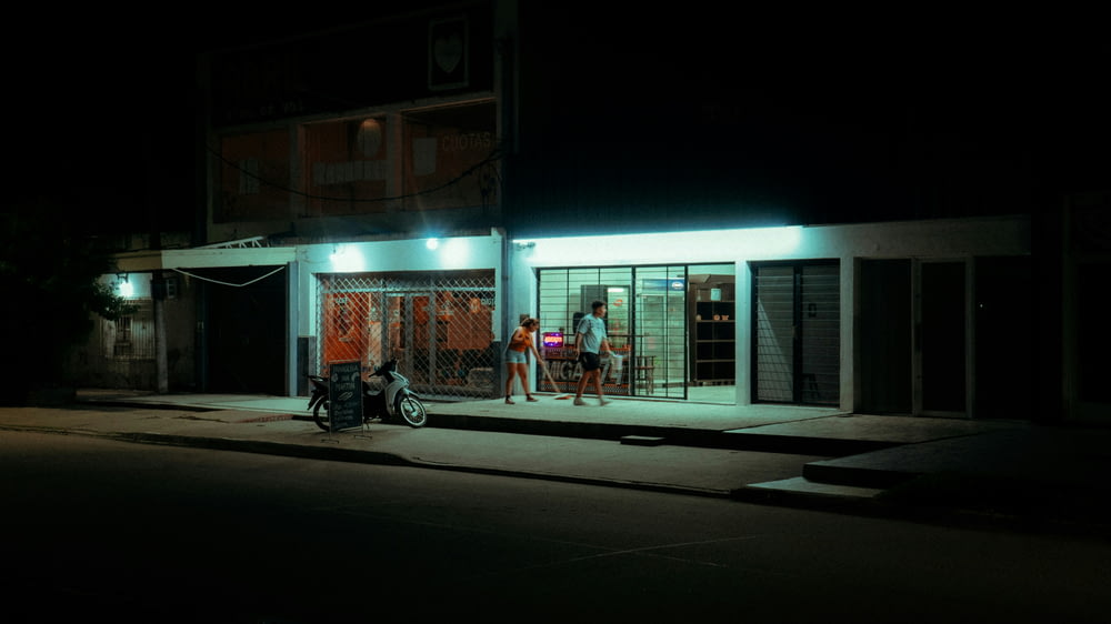 a man standing outside of a store at night