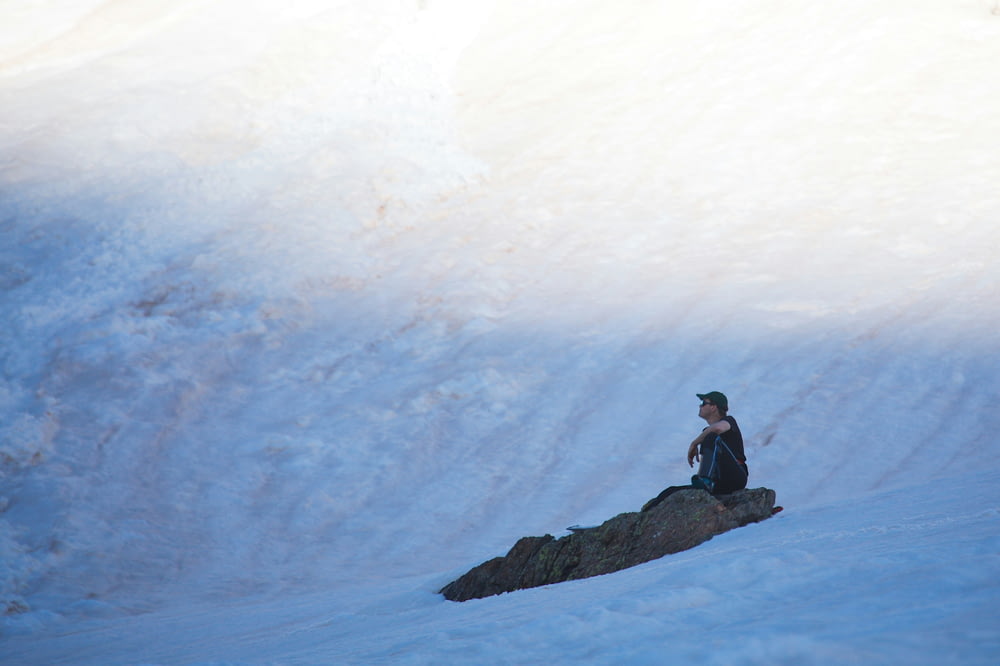 une personne assise sur un rocher dans la neige