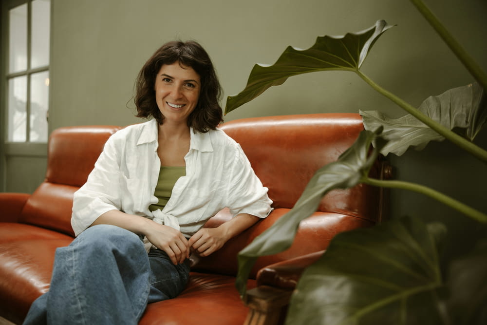 a woman sitting on a couch smiling for the camera