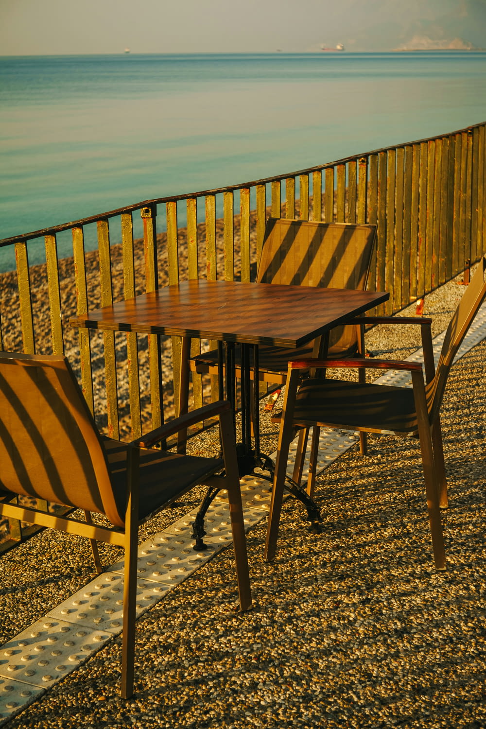 a wooden table and chairs sitting on a beach