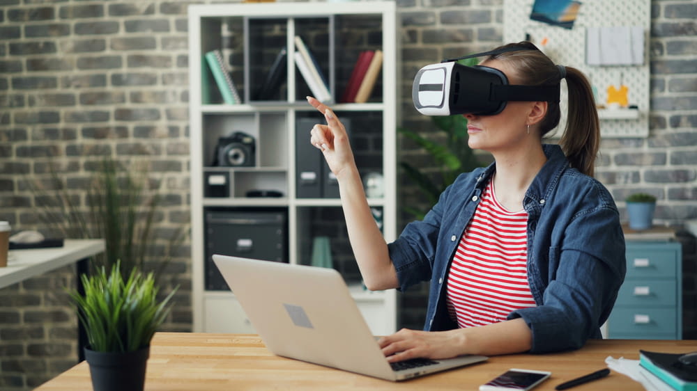 a woman using a laptop while wearing a virtual headset
