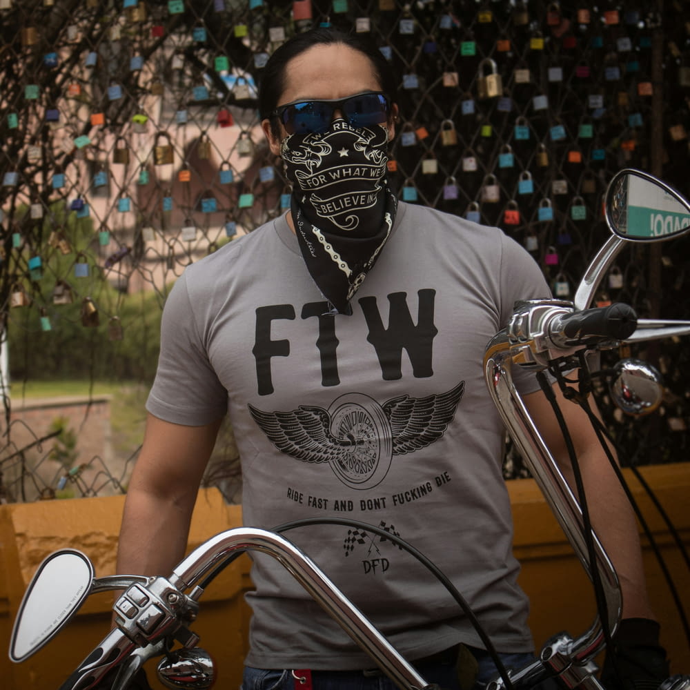 a man with a bandana on his face standing next to a motorcycle