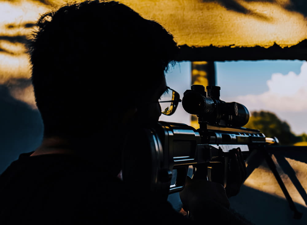 a man holding a rifle and aiming it at a target