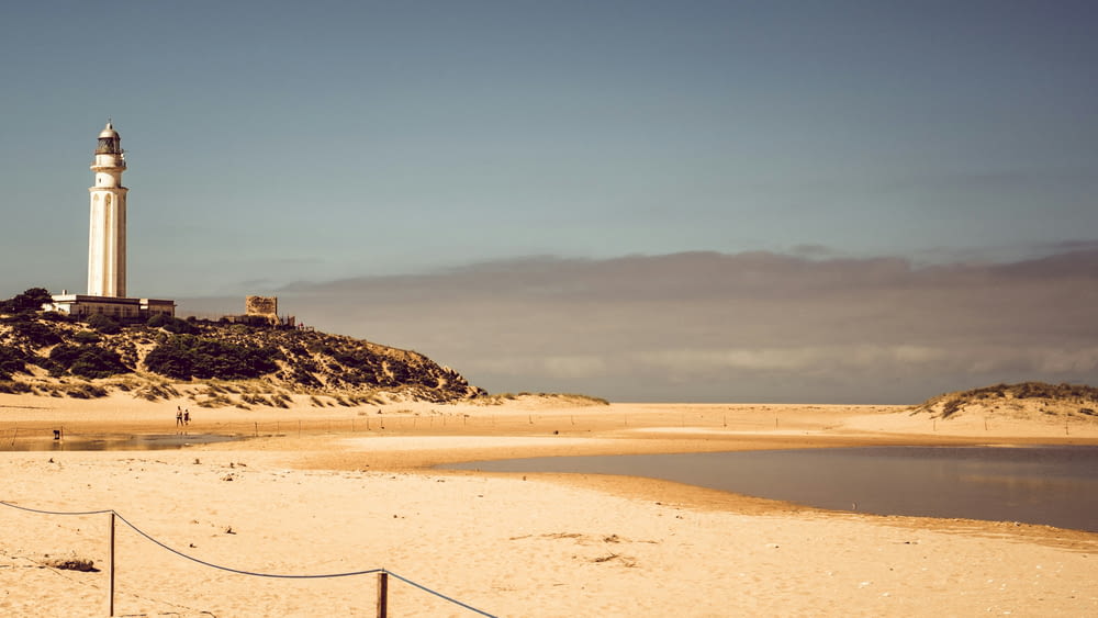 um farol sentado em cima de uma praia de areia