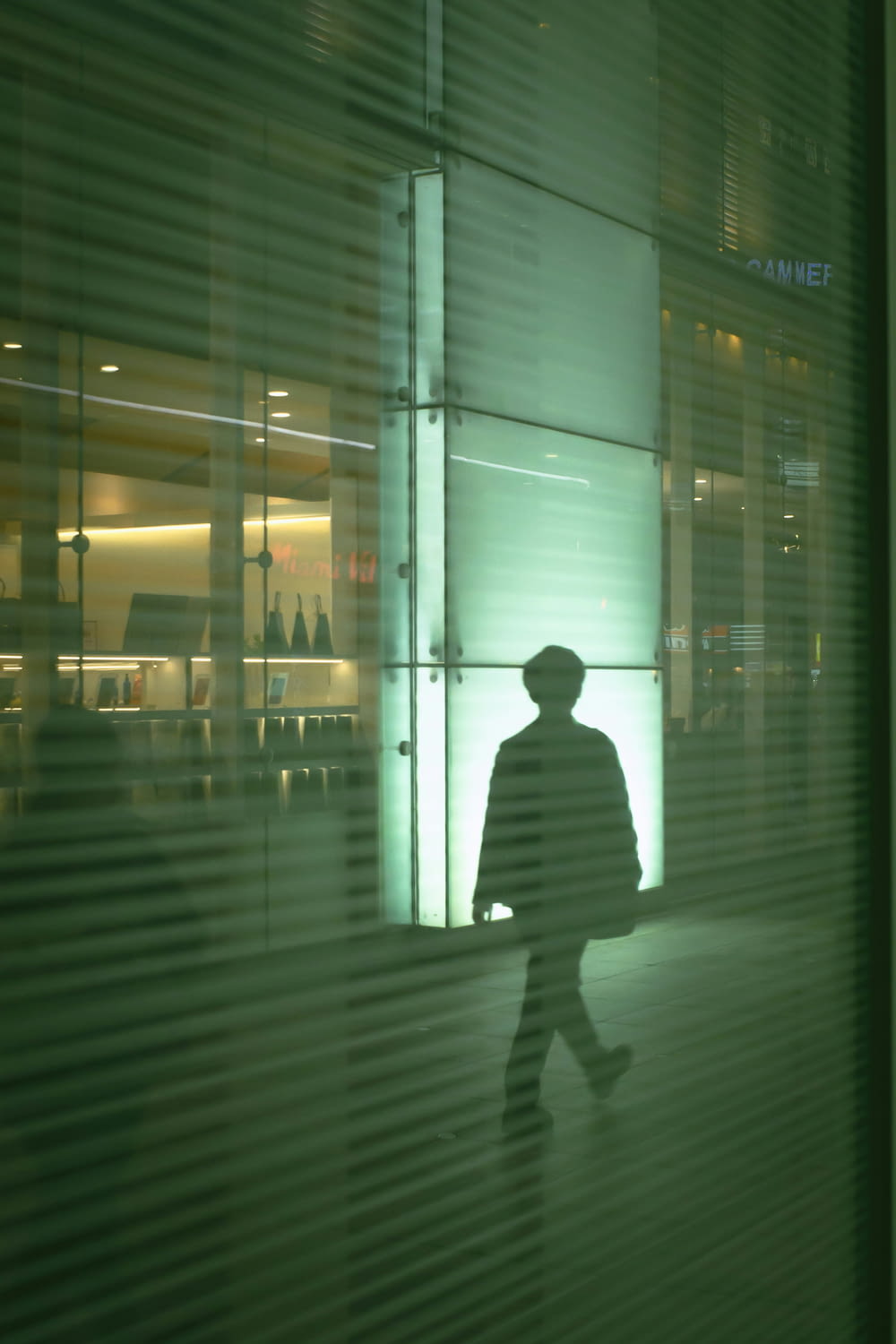 a silhouette of a man walking past a window