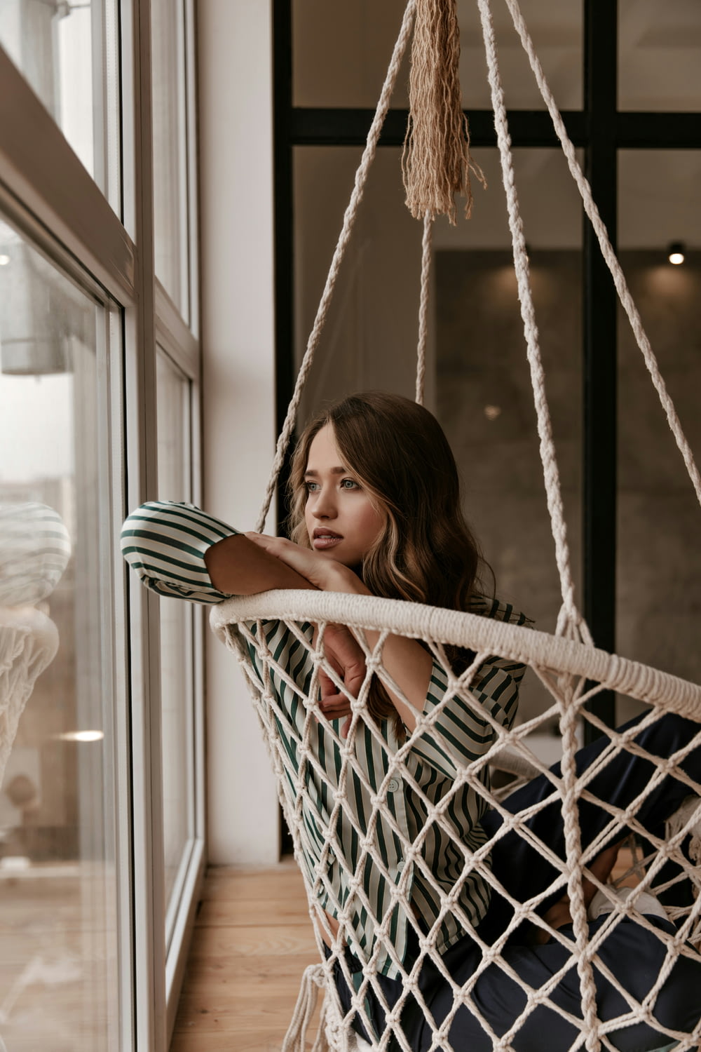 a woman sitting in a hammock looking out a window