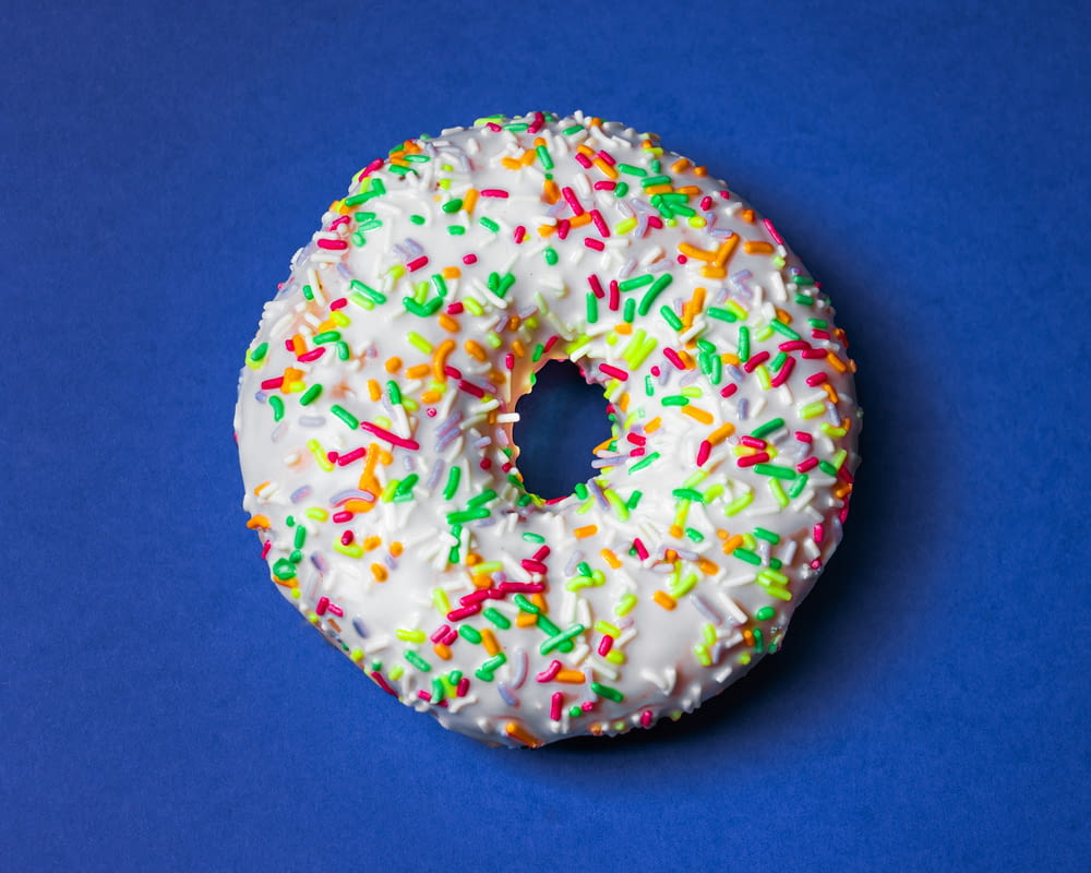 a sprinkled donut with white frosting and colored sprinkles