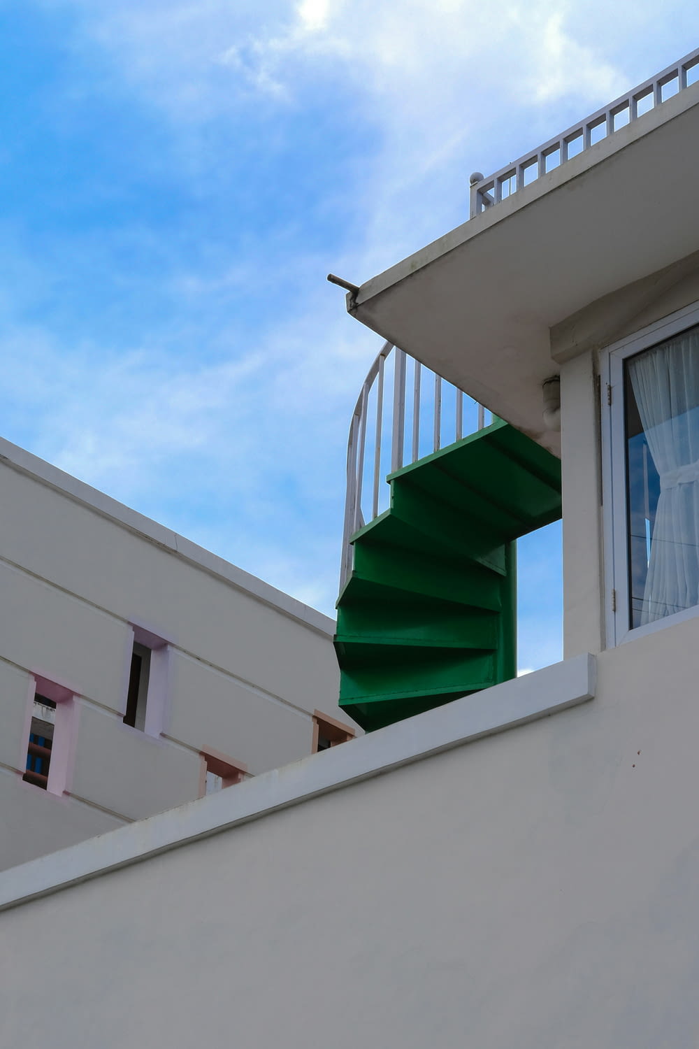 a white building with a green spiral staircase