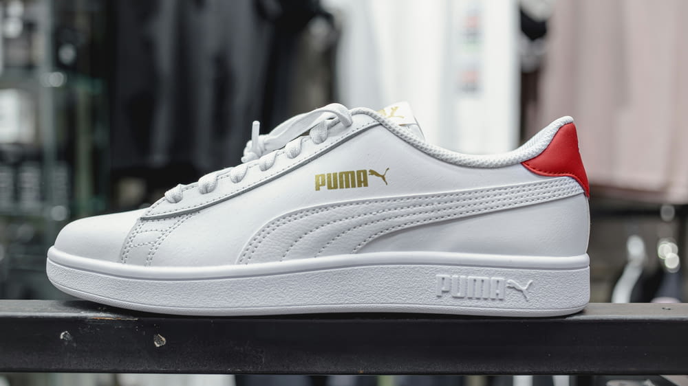 a white and red puma sneakers sitting on top of a table