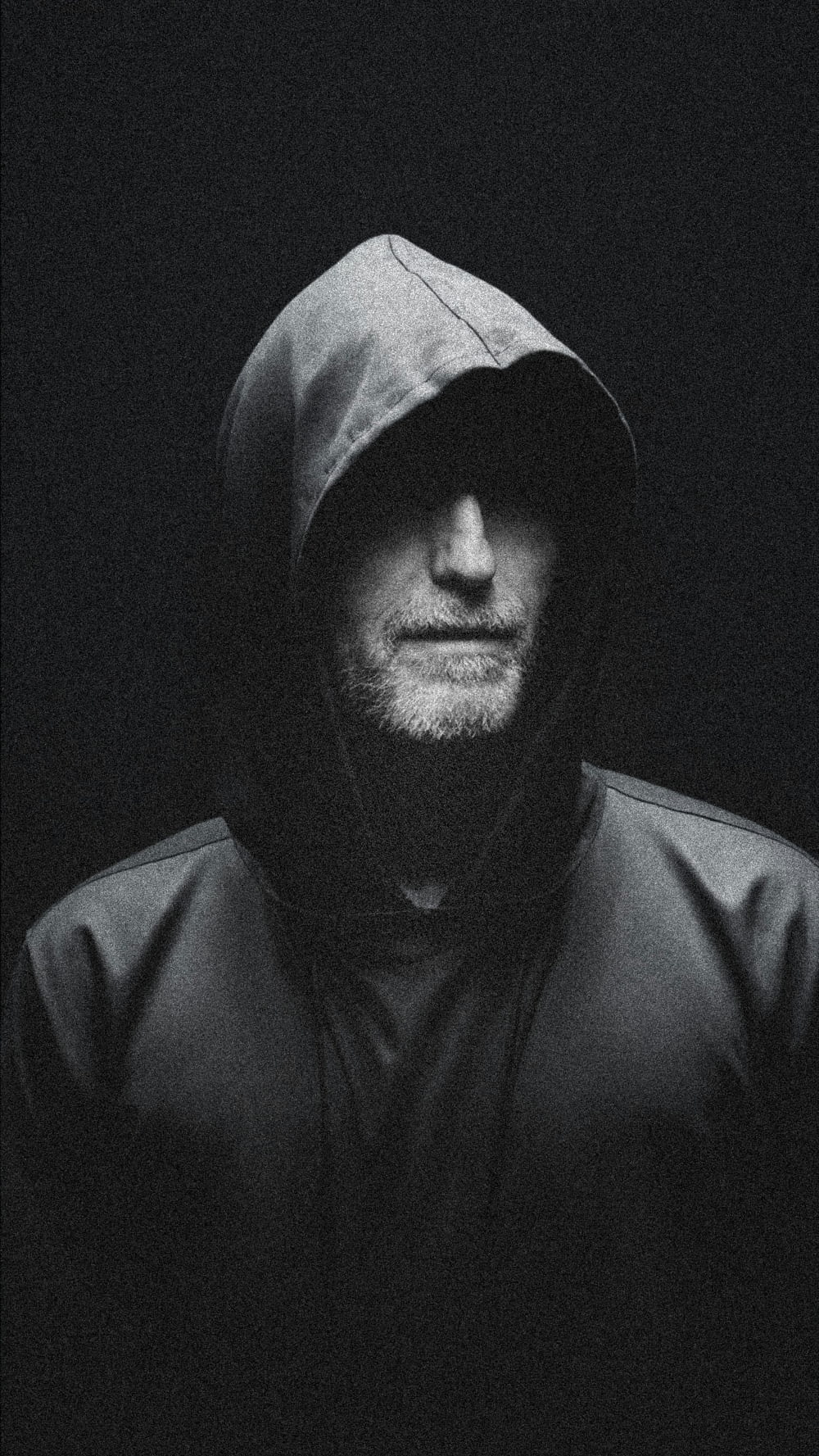 a man wearing a hoodie in the dark