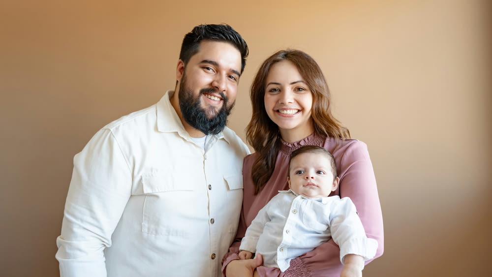 a man and woman pose for a picture with a baby