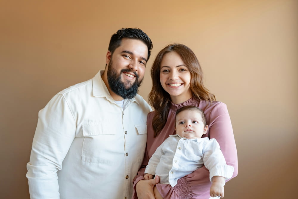 a man and woman pose for a picture with a baby