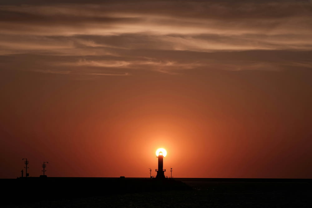 Le soleil se couche derrière un phare sur l’océan