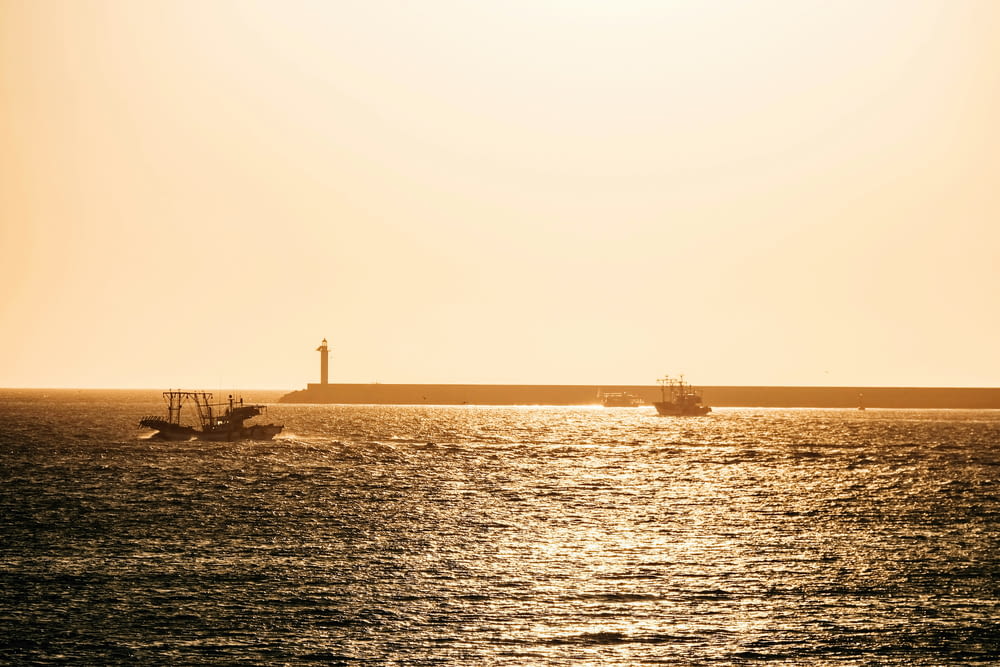 deux bateaux dans l’eau près d’un phare