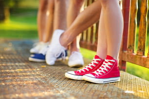 歩道に立つ10代の少年少女の脚とスニーカー