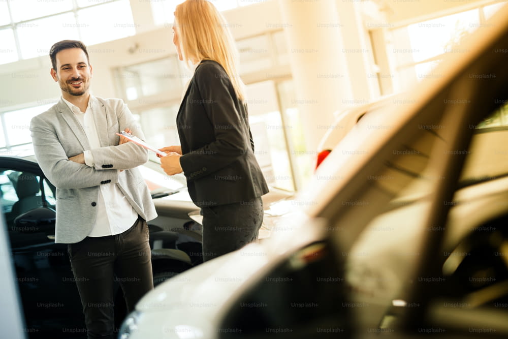 Salesperson showing vehicle to potential customer in dealership