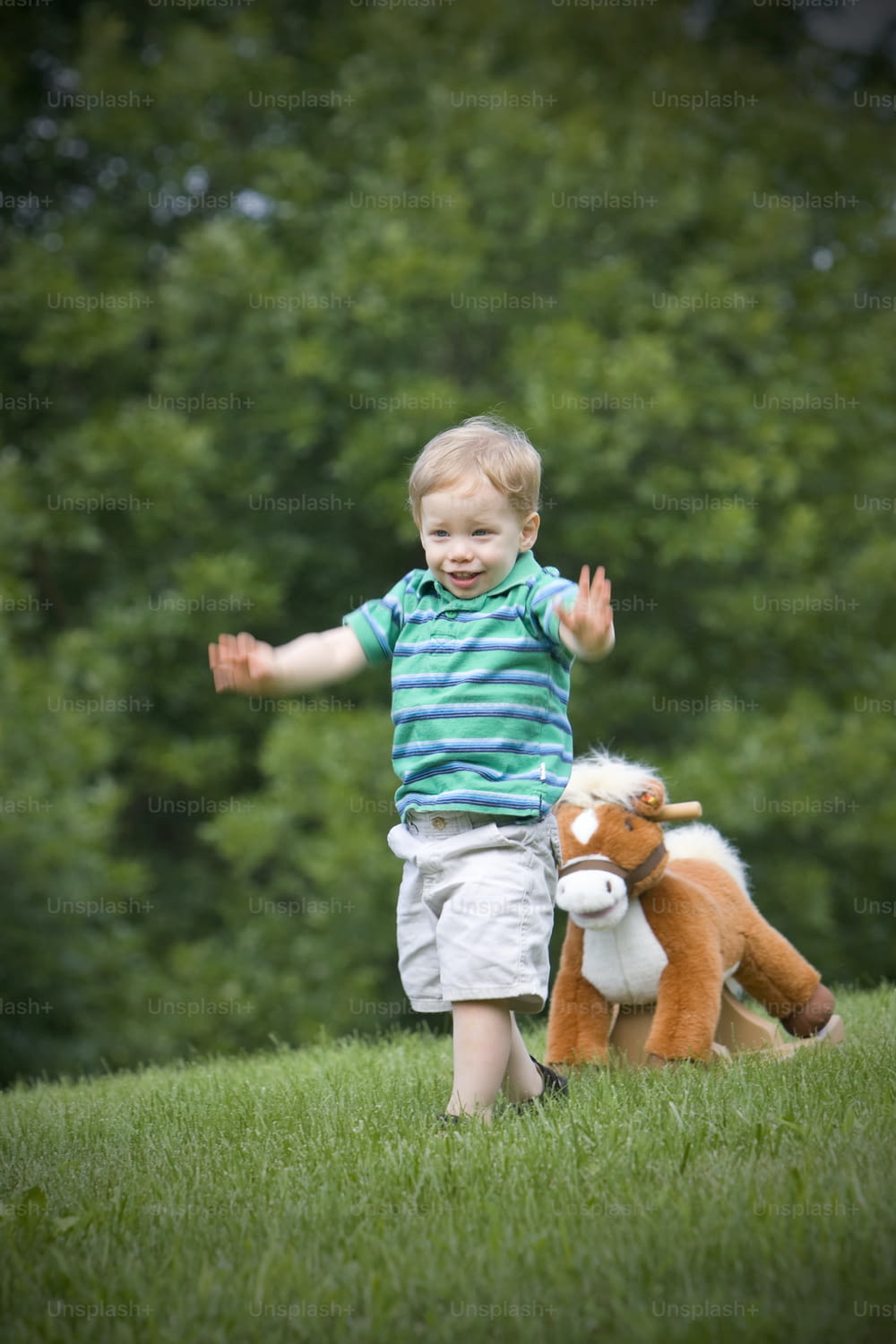 Un petit garçon debout dans l’herbe avec un animal en peluche