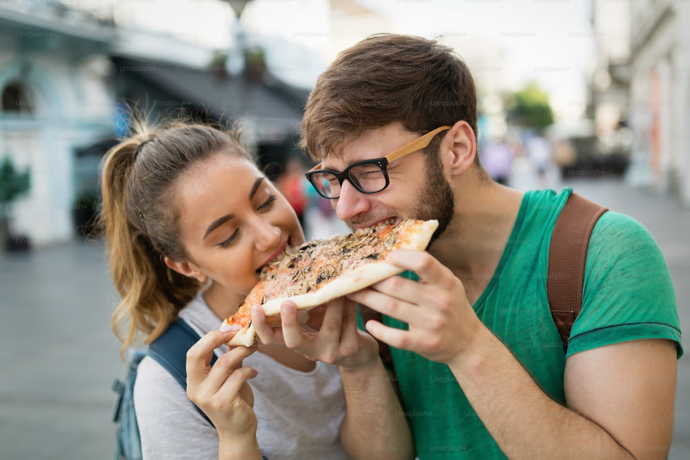 Glückliche Gruppe von Freunden, die Pizza im Freien essen