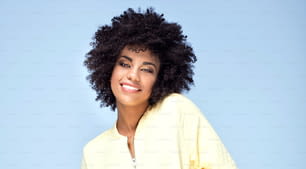 Fashionable beautiful african american woman posing on blue background, smiling.