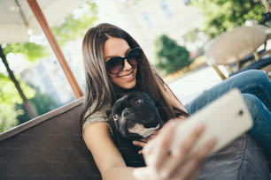 Bella ragazza adolescente seduta nel ristorante del caffè con il suo adorabile cucciolo di bulldog francese. Tema persone e cani.