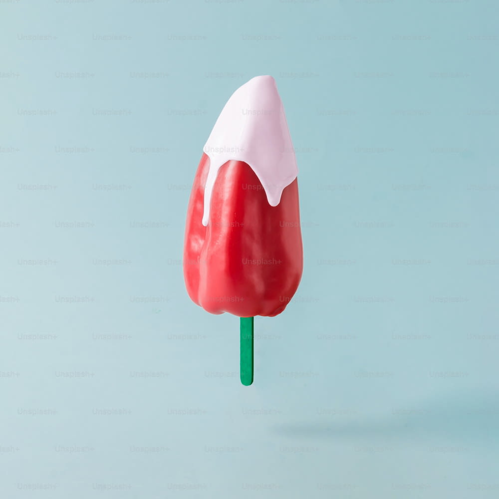Red pepper with ice cream stick on pastel blue background. Food creative concept.